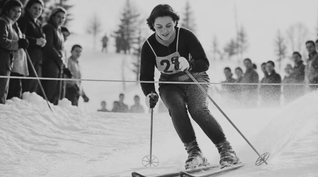 Skieuse alpine franchissant une ligne d’arrivée enneigée